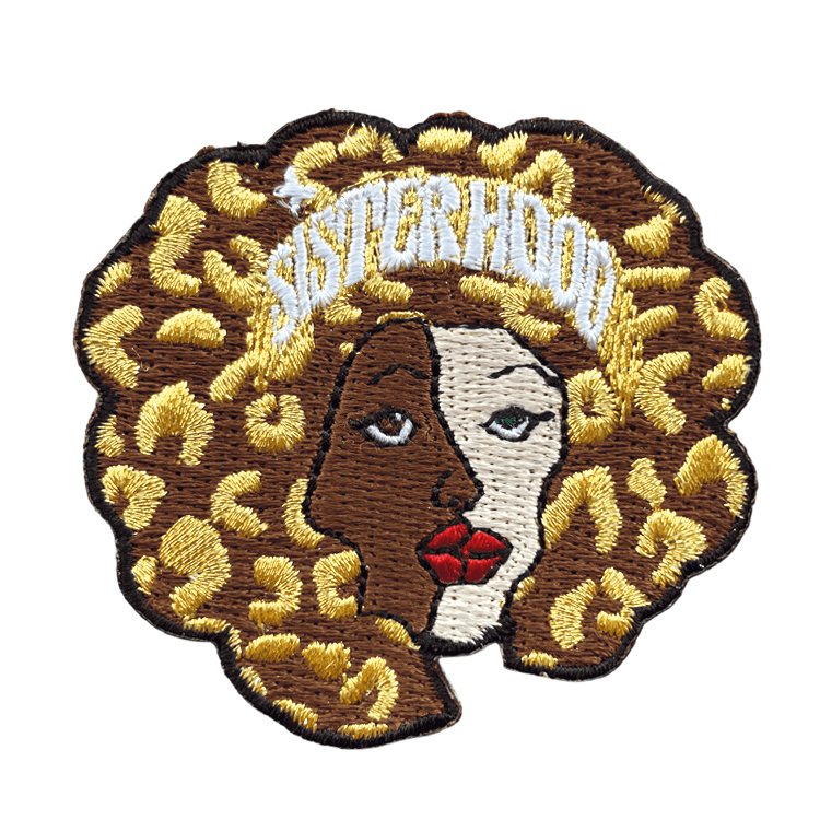 Patch thermocollant funky avec deux visages féminins fusionnés, une crinière léopard dorée, et "Sisterhood" qui claque en haut.